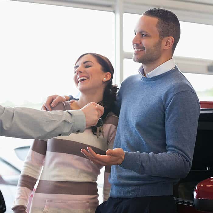 Business Loans for Car Sale Dealerships - Customer receiving car keys in car showroom