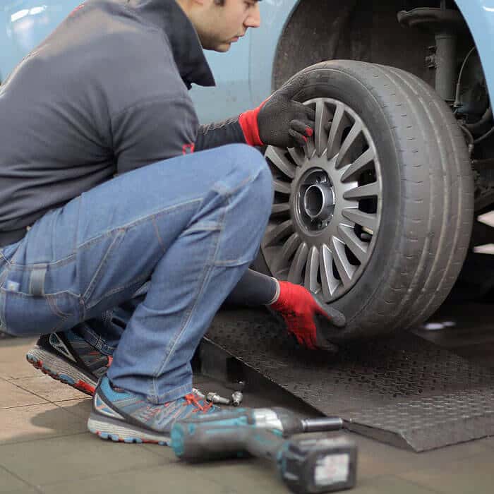 Business Loans for Garages and MOT service centres - Mechanic replacing alloy wheel on car