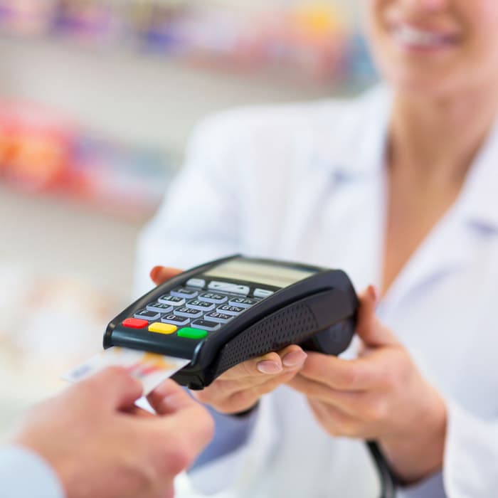 Pharmacist accepting credit card payment from customer