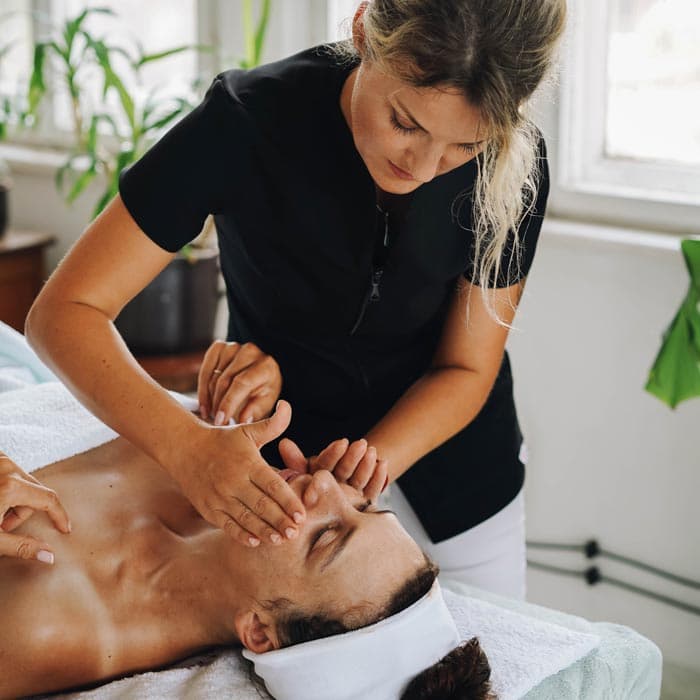 Massage therapist treating customer to facial in an independent spa business